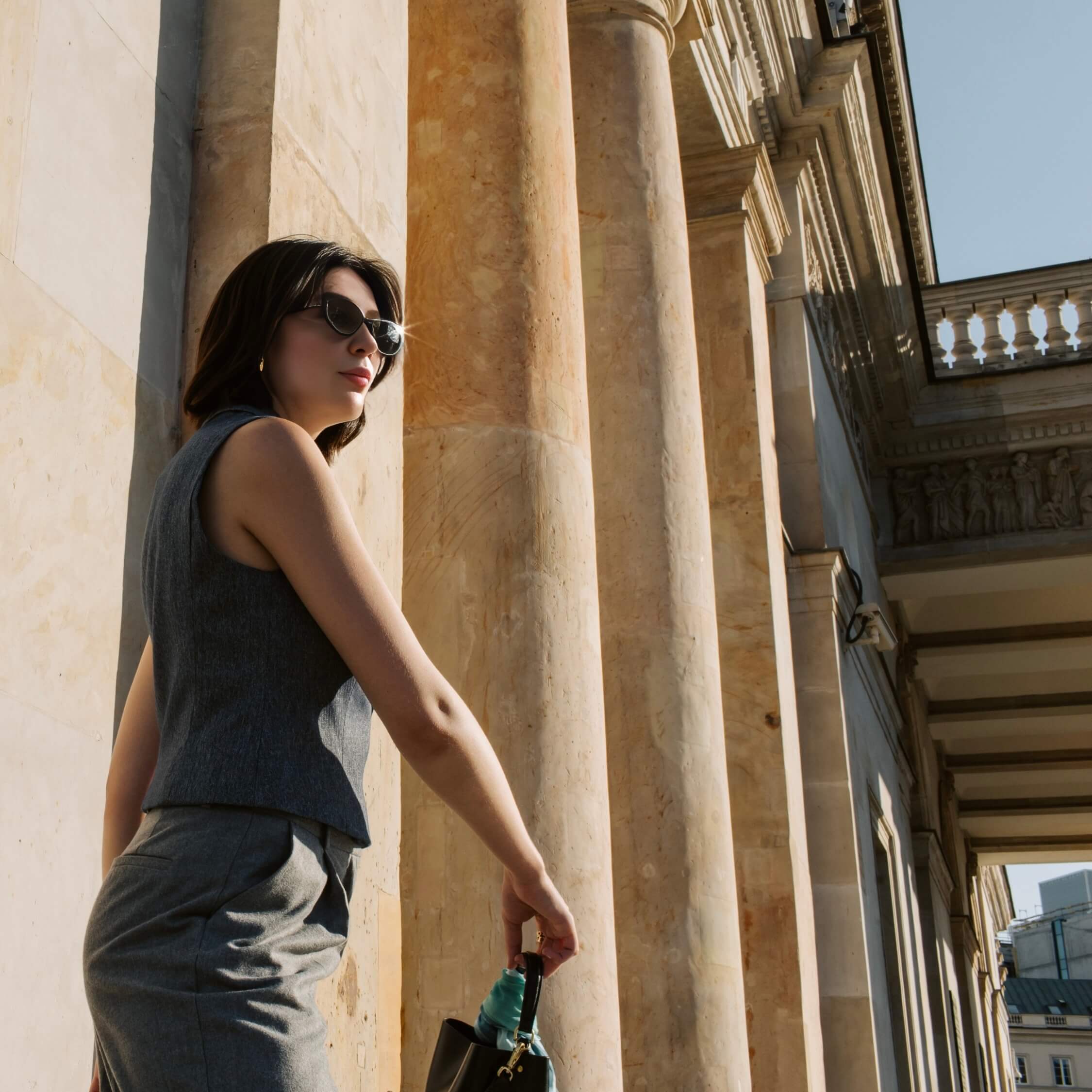 Anna Kozachenko stands in sunlight next to a row of stone columns